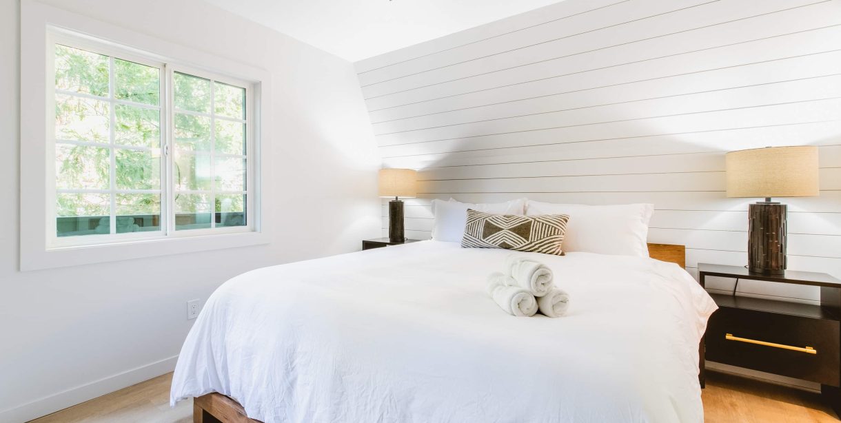 Cozy room with a white bed and window view at a boutique hotel near the Village.