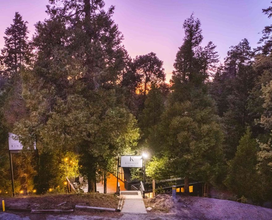 A scenic sunset view at a Lake Arrowhead Lodging surrounded by tall evergreen trees.