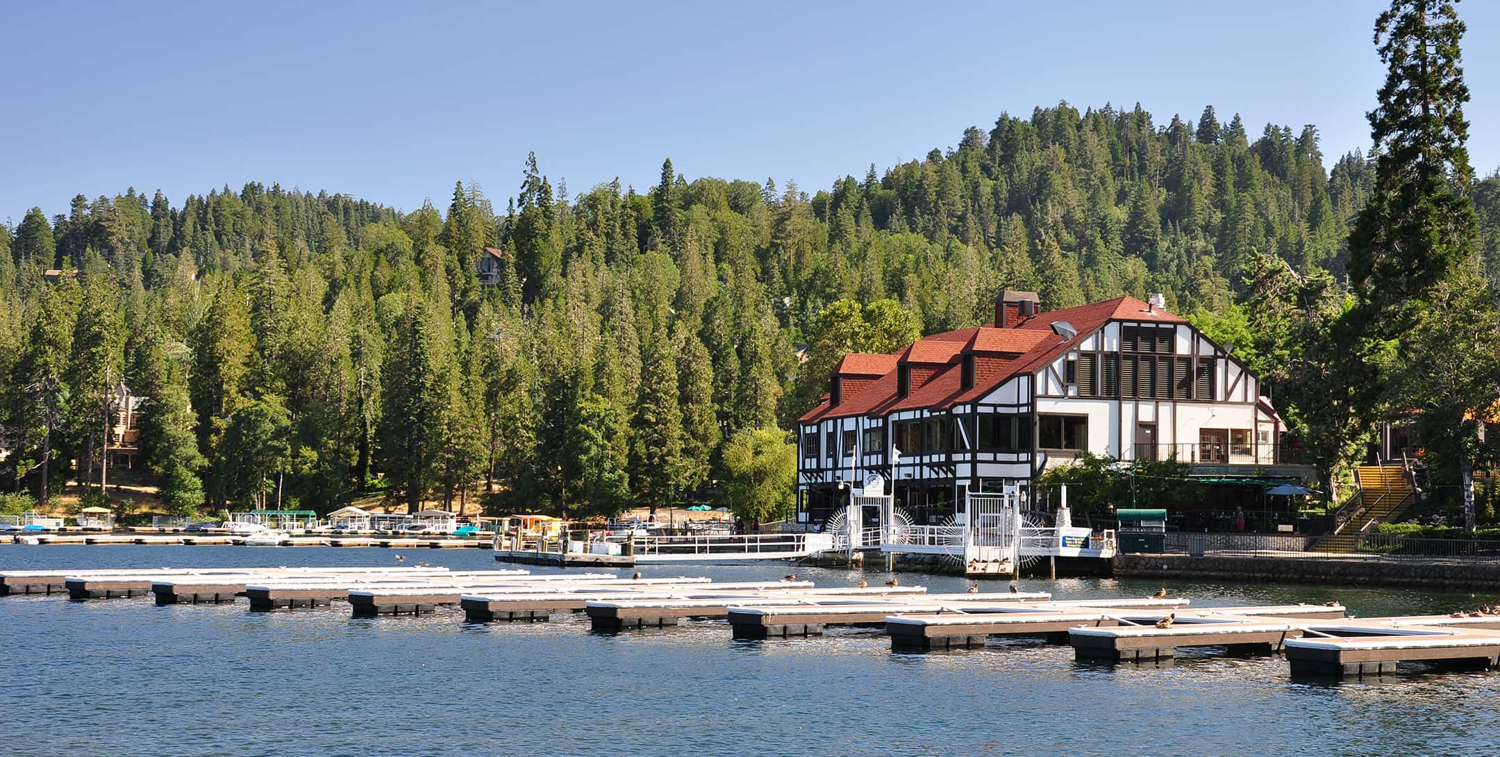 Charming lakeside view of a hotel nestled in the forest, ideal for a Lake Arrowhead Escape.